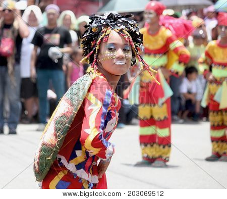 DAVAO CITY, PHILIPPINES--AUGUST 2014: A girl with painted face and colorful headdress dancing at the streets.
Kadayawan is celebrated August each year to give thanks for life and an abundant harvest.