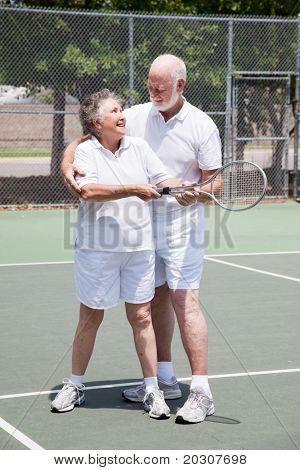 Mujer bastante senior recibe una lección de tenis de su marido guapo.