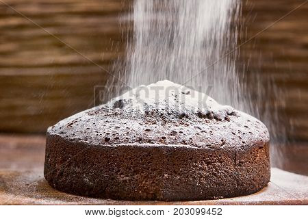 Delicious chocolate cake in white plate on wooden table background, closeup