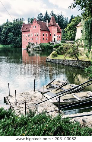 Cervena Lhota chateau with small boats in the lake Czech republic. Travel destination. Blue photo filter.