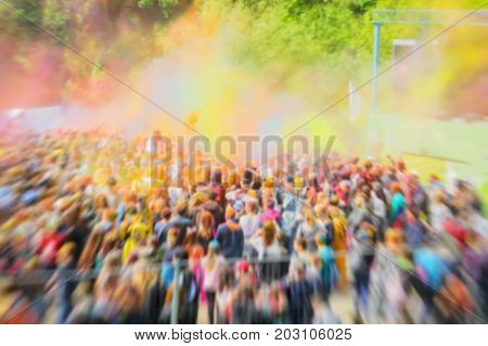 Blurred unrecognizable happy young people celebrate Holi festival. Colorful vivid powder explosion