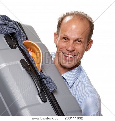 Young cheerful tourist holding big gray valise