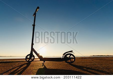 Kick scooter on asphalt running track , under sunlight at sunny summer day. Wide angle image.