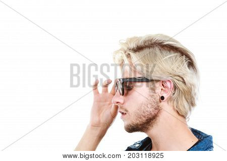 Men fashion accessories hairstyle modeling concept. Artistic hipster blonde man wearing and holding sunglasses profile portrait studio shot isolated