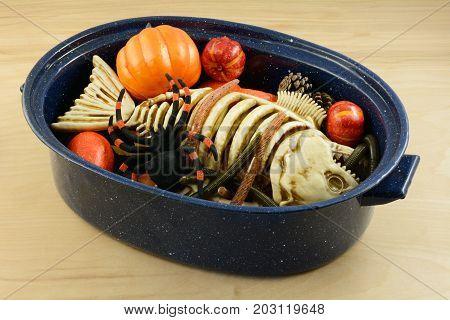 Halloween witch's brew of worms, dead fish skeleton, spider, pine cones and pumpkins in large pan