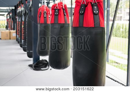 red and black sandbag for hitting and punching in boxing gym. sport fitness lifestyle concept.
