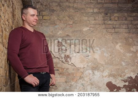 Portrait of adult man staying against the background of a peeling wall. Studio shoot