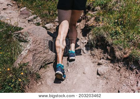 Muscular calves of a young athlete running up a mountain path ultramarathon and skyranning
