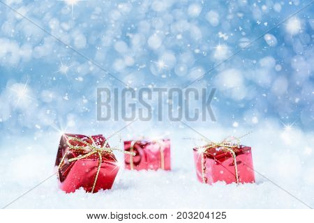 Red christmas presents with snow and stars on a blue background for a greeting card or voucher.Selected focus narrow depth of field.