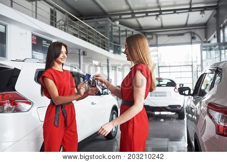 auto business, car sale, deal, gesture and people concept - close up of dealer giving key to new owner in auto show or salon.