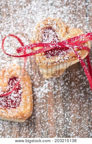 Jam filled heart cookies with ribbon and icing sugar closeup.