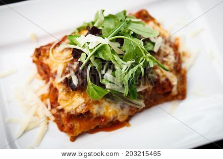 Lasagna served on a white plate with salad
