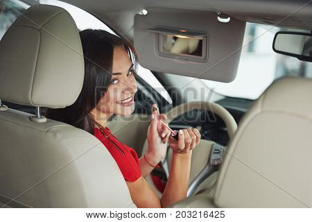 woman in car indoor keeps wheel turning around smiling looking at passengers in back seat idea taxi driver against sunset rays Light shine sky Concept of exam Vehicle - second home the girl.