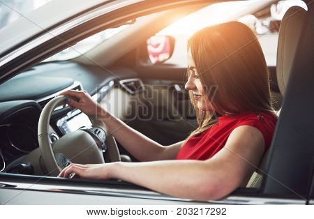 woman in car indoor keeps wheel turning around smiling looking at passengers in back seat idea taxi driver against sunset rays Light shine sky Concept of exam Vehicle - second home the girl.