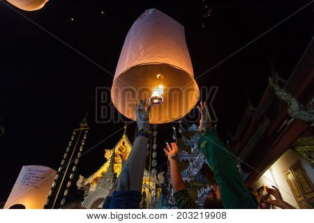 CHIANG MAI THAILAND - 12/30/2015: A group of tourists release floating lanterns at a Buddhist temple on New Year's Eve in Chiang Mai Thailand.
