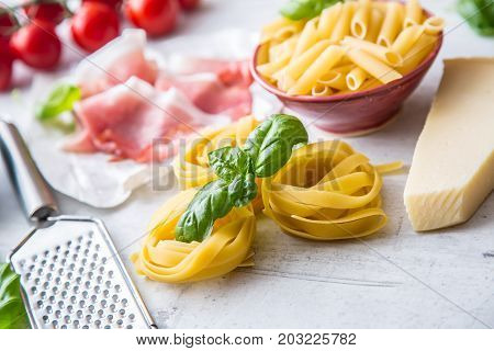 Italian Or Mediterranean Food Cuisine And Ingredients On White Concrete Table. Tagliatelle Pene Past