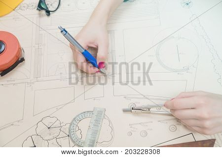 Architect drawing on a blueprint with a compass and ruler.