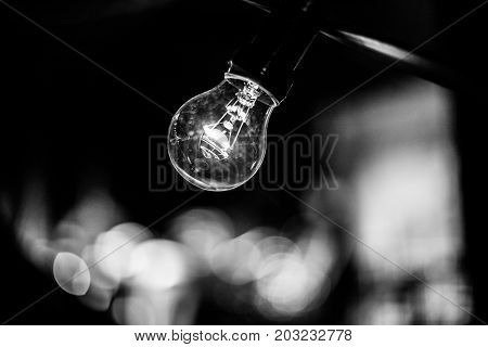 A lamp bulb of glass hanging on a black cord