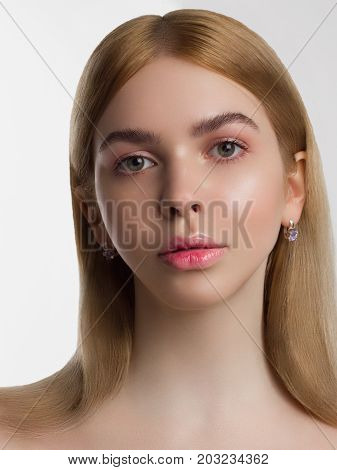 Portrait of the beautiful young girl with a day make up and equal skin. Gently pink gloss of lipstick on chubby sensual lips. Spa cosmetology