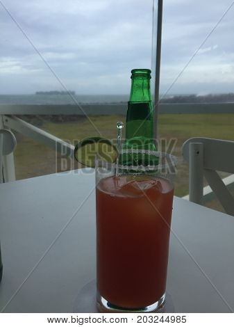 se ve una bebida con clamato y al fondo la isla de enmedio