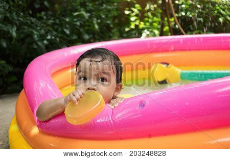 Baby boy play water in kiddie pool by alone