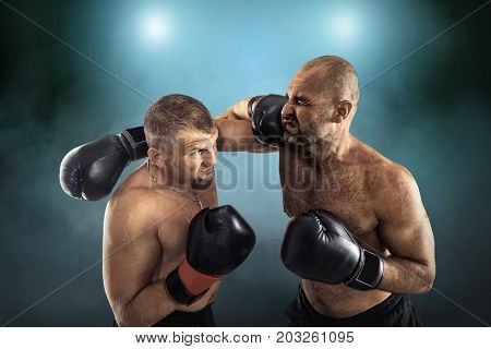 Two professional boxers, athletes in dynamic boxing action on the ring under lights of sport arena.