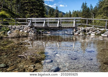 Wooden bridge trail at Morskie Oko alpine lake on sunny day, Tatry Mountains, Poland
