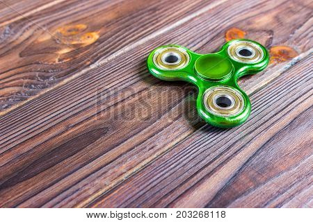 Green fidget spinner stress relieving toy on wood background