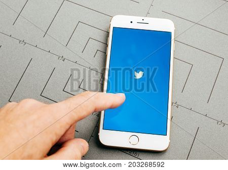 PARIS FRANCE - SEP 26 2016: Male hand holding New Apple iPhone 7 Plus after unboxing and testing by installing the app application software Twitter app sign in finger
