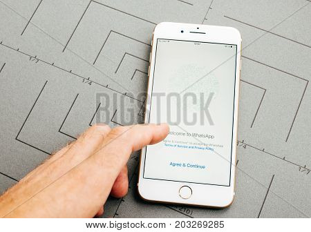 PARIS FRANCE - SEP 26 2016: Male hand holding New Apple iPhone 7 Plus after unboxing and testing by installing the app application software WhatsApp agreement prior use