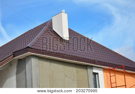 Construction or repair of the rural house with eaves windows chimney roofing fixing facade insulation plastering and painting walls. Painting House Facade Wall. Metal Tiled Roofing.