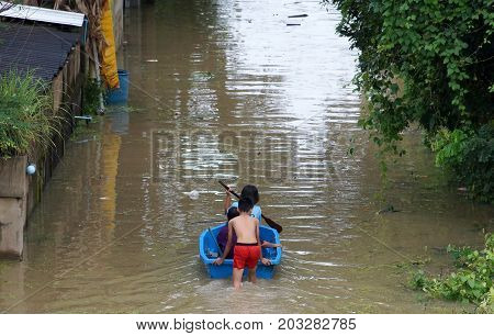 People rowing a boat through a flooded street in Thailand