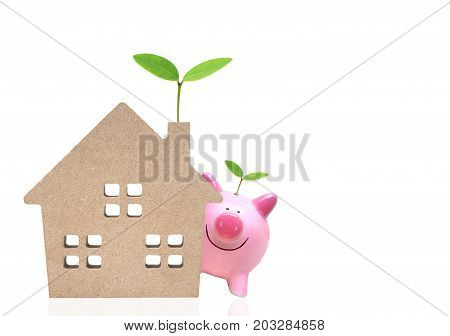 A pink piggy bank and a wooden house with green trees / Saving money for buying eco-house concept