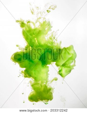 Ink swirl in water isolated on white background. The paint in the water. Soft dissemination a droplets of green ink in water close-up. Abstract background. Soft focus.