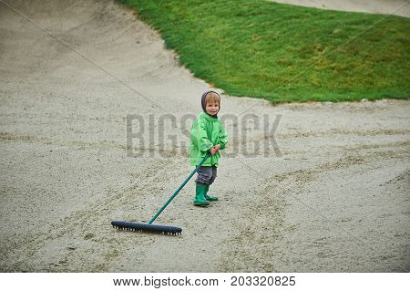 boy walking the golf course with a rake