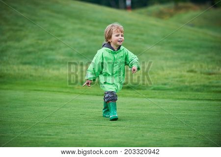 little boy walking the green golf course