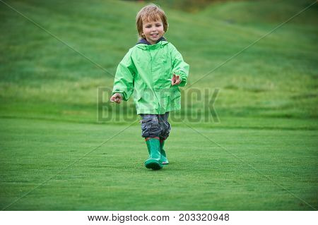 little boy walking the green golf course