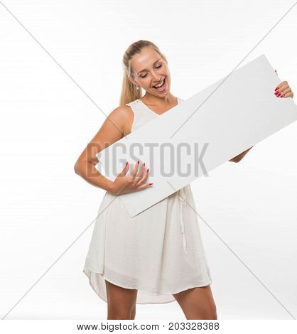 Young jocular woman portrait of a confident businesswoman showing presentation, pointing placard gray background. Ideal for banners, registration forms, presentation, landings, presenting concept.