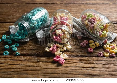 Close-up of scattered honeycomb cereals from jar on wooden table
