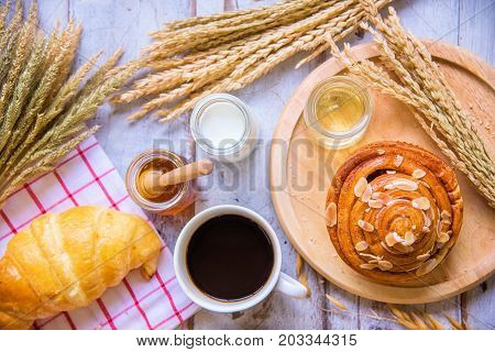Fresh tasty bread with coffee and honey bee with milk on the table.
