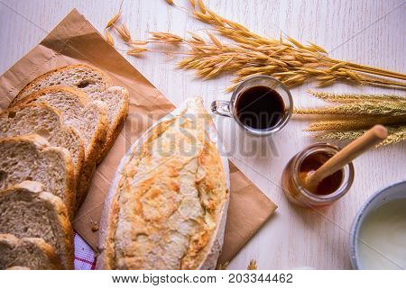 Fresh tasty bread with coffee and honey bee with milk on the table.