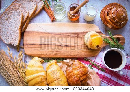 Fresh tasty bread with coffee and honey bee with milk on the table.