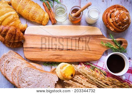 Fresh tasty bread with coffee and honey bee with milk on the table.