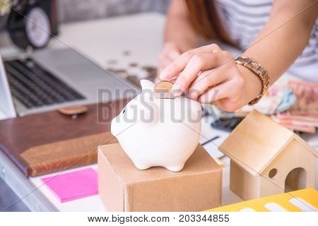 Coins on hand are dropped Piggy bank on wooden top table money savings concept