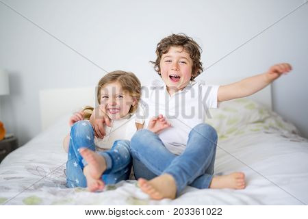 A Brother And Sister Relaxing Together In Bed