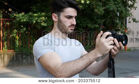 Handsome young male photographer or videomaker shooting video footage with professional photo camera
