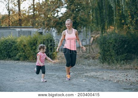 mom and little daughter running in summer park