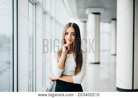 Attractive Young Businesswoman Portrait With Hands On Chin Near Office Windows