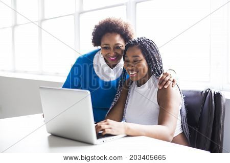 A Mother And Teenage Daughter Looking At Laptop Together