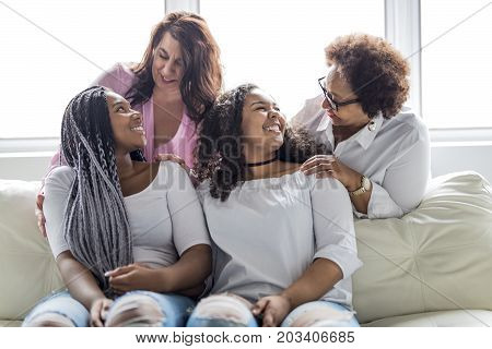 Two family Friends Sitting On Sofa Together having fun